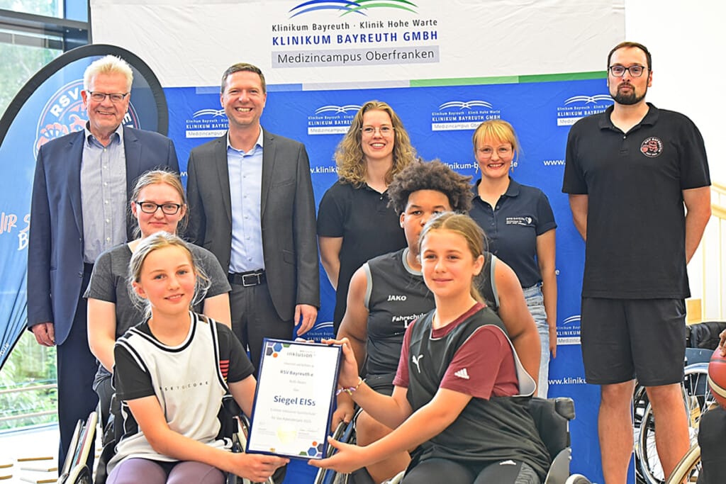 Kinder halten Urkunde mit Siegel und im Hintergrund stehen RSV Mitglieder