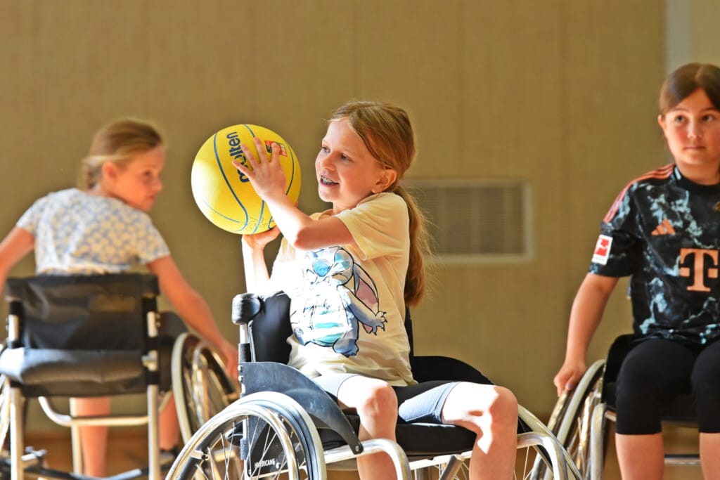 Kinder spielen Rollstuhlbasketball in der Mitte ein Mädchen das Ball wirft