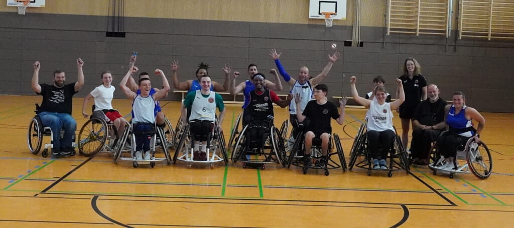 Gruppenaufnahme der SG Weiden-Bayreuth mit Spielerinnen, Spielern und Betreuungsteam in der Sporthalle.